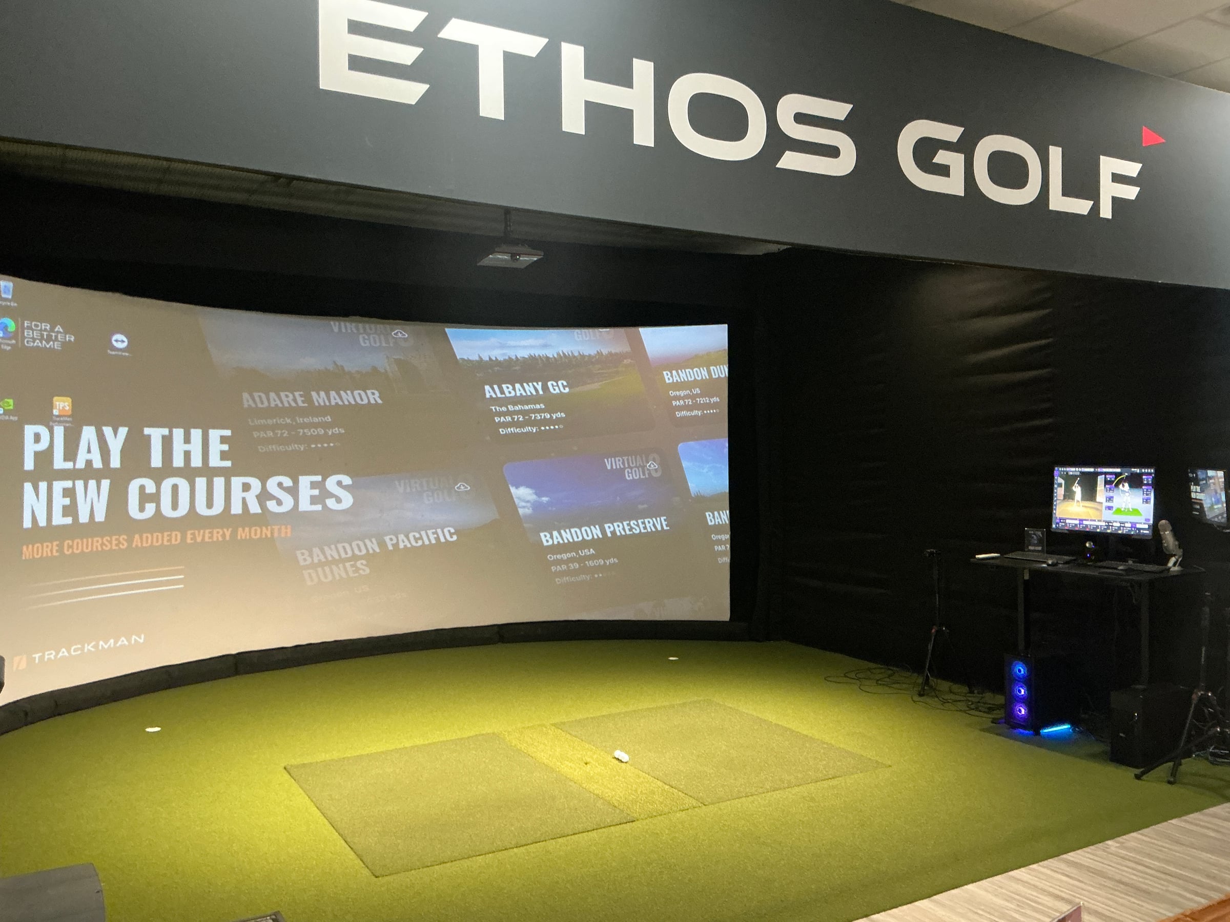 Ethos Golf - Allen — Private practice bay: ETHOS GOLF cut into the black wall above a wide TrackMan screen, wid